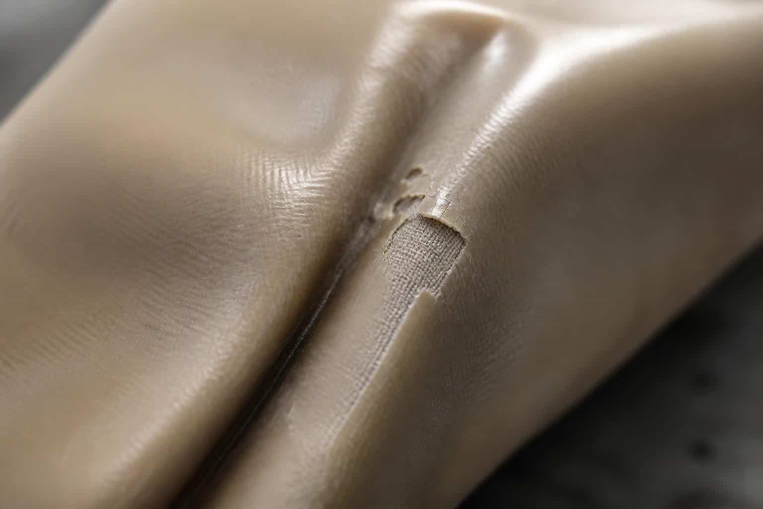 Fold fatigue on a pillow tank's TPU-coated fabric, showing coating microcracks and delamination at the crease line